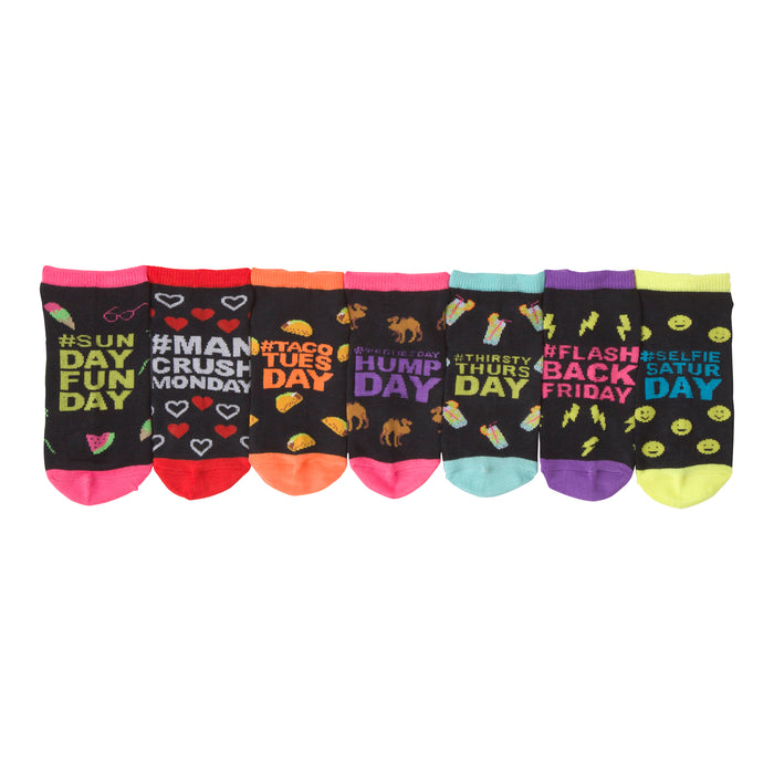 Seven pairs of ankle socks. Each black sock has a different day-of-the-week design with bright accents. Designs include watermelon, hearts, tacos, camels, and cocktails. }}