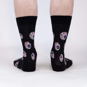 Rear view of a pair of black crew socks with an eyeball pattern.