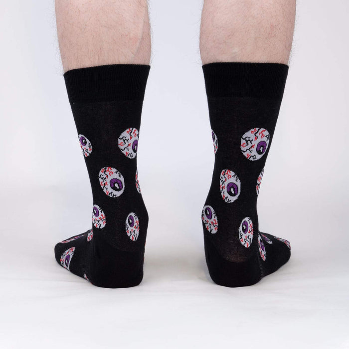 Rear view of a pair of black crew socks with an eyeball pattern.