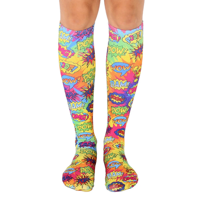 Knee-high socks in a tie-dye pattern of bright yellow, pink, and blue.  Comic book-style words like 'POW!' and 'BAM!' are printed throughout.