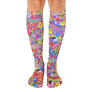 Knee-high socks in pink, yellow, and other bright colors. Features a fun, collage-style design of NYC imagery like smiley faces, pizza, and traffic lights.