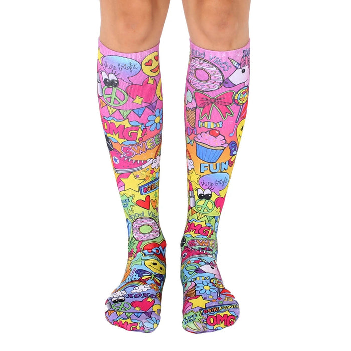 Pair of knee-high socks. Pink base with colorful cartoon designs, including unicorns, cupcakes, and peace signs.