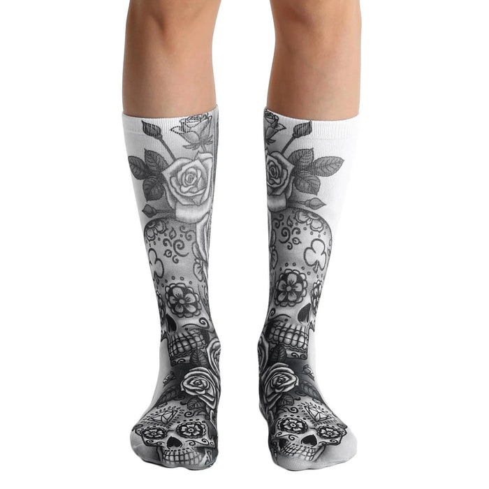 A pair of white crew socks with a gray sugar skull and rose design. The skulls have floral details.
