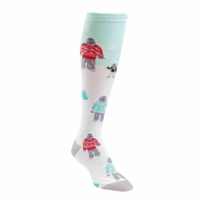 Knee-high socks in white with a teal background. The design features Yetis in red and teal sweaters, a small dog, and tiny trees. }}