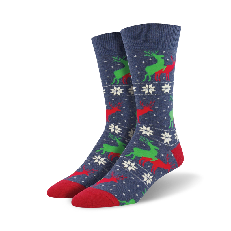 A pair of navy blue crew socks with a repeating pattern of red and green reindeer and white snowflakes. The socks have red toes and heels.