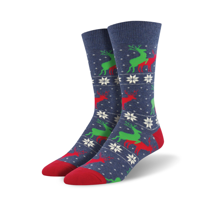 A pair of navy blue crew socks with a repeating pattern of red and green reindeer and white snowflakes. The socks have red toes and heels. }}
