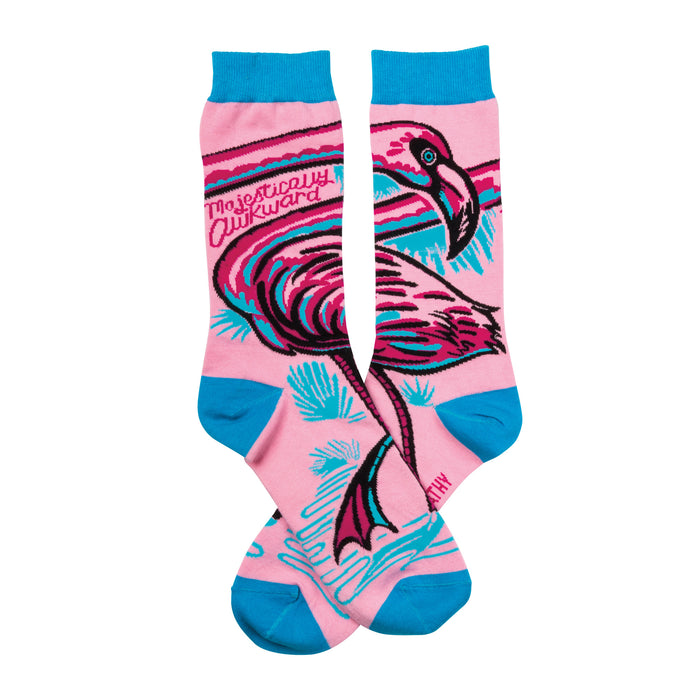 Pair of pink crew socks with a teal and black flamingo design. The words 'Majestically Awkward' are written on the socks. }}