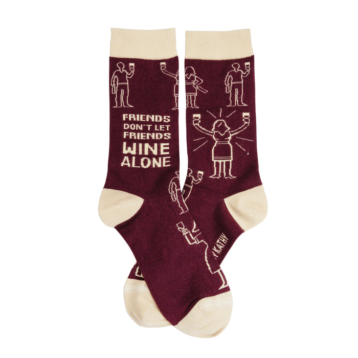 A pair of burgundy crew socks with a beige cuff and toe.  The socks feature a pattern of stick figures drinking wine and the text 'Friends don't let friends wine alone'. }}