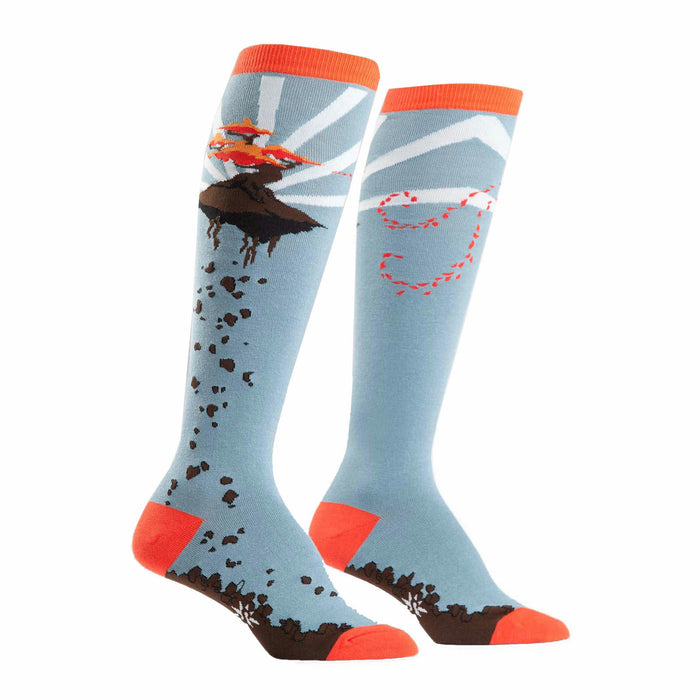 A pair of knee-high socks in light blue, orange, and brown. One sock shows a flying bonsai tree; the other has a whimsical trail design. }}