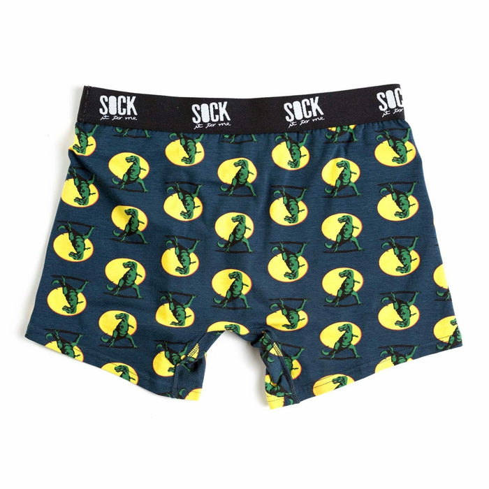 Dark teal men's boxer briefs with a repeating pattern of green T-Rex dinosaurs in yellow circles. The waistband says 'SOCK it to me'. }}