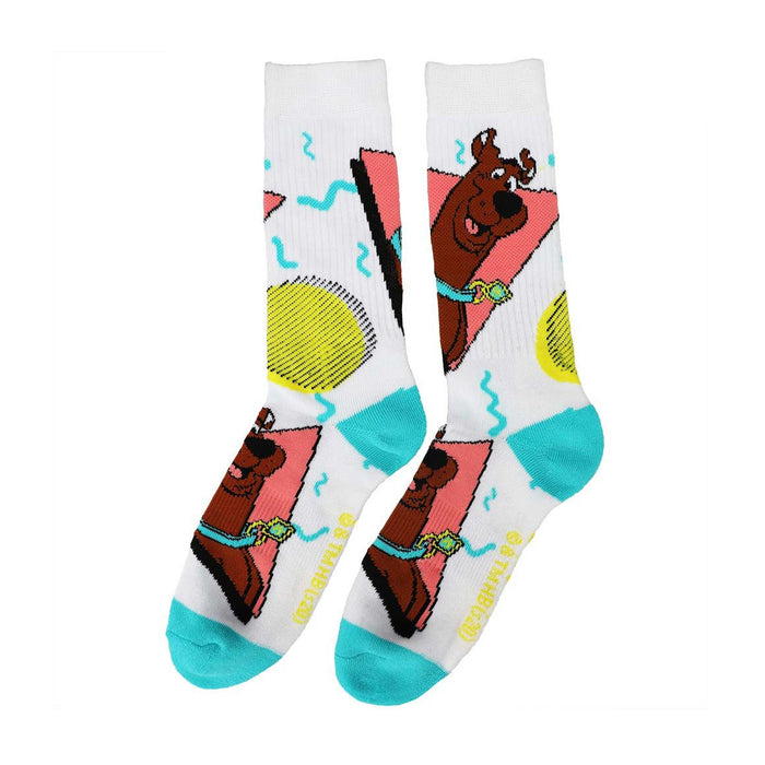 A pair of white socks with a pattern of Scooby Doo, a cartoon character, wearing a pink collar with a gold tag. The background is filled with colorful geometric shapes.