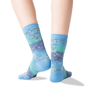 A pair of blue socks with a Monet-like painting of a pond with water lilies on them.