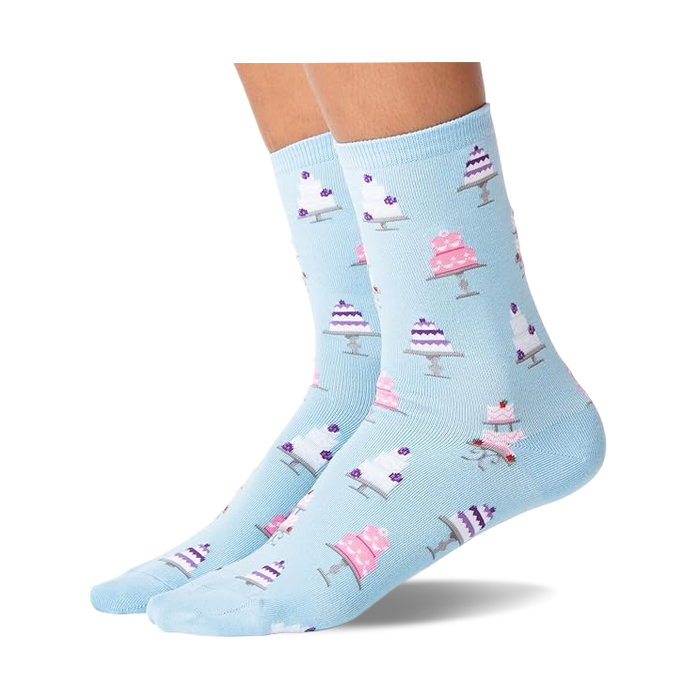 Pair of feet wearing light blue socks with white and pink wedding cake patterns, shown against a white background.