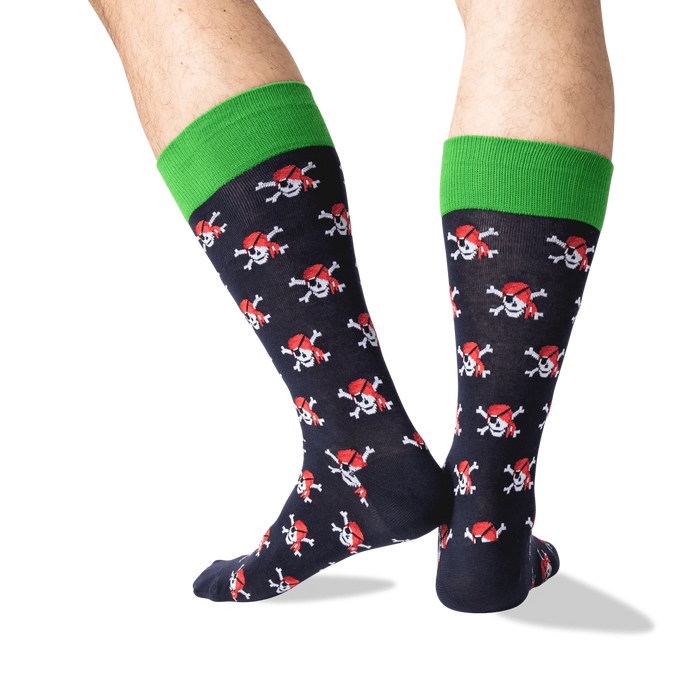 A pair of black socks with a green band at the top and a pattern of red pirate skulls with black eye patches and crossed bones.