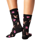 Back view of a pair of black crew socks with a hummingbird and flower pattern.