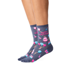 Lifestyle shot showcasing a woman's legs wearing the dark grey 'Happy Birthday' crew socks. The socks' design is clearly visible.