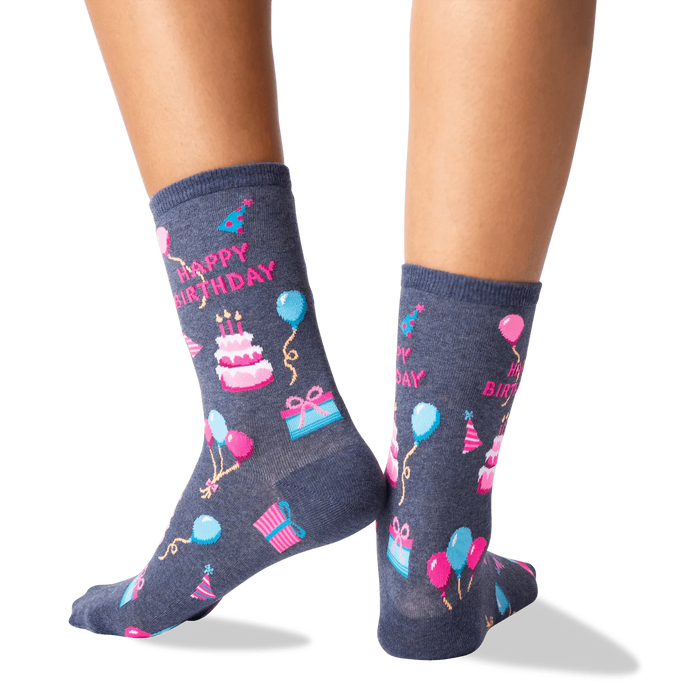 A pair of gray socks with a colorful pattern of birthday-related items, including balloons, presents, hats, and cakes.
