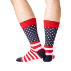 Rear view of the American Flag socks on a person's legs against a green background. The socks are red, white, and navy.
