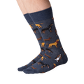 Lifestyle shot showing a person wearing a pair of dark grey crew socks with a repeating pattern of various dog breeds.