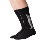 Lifestyle shot of a person's legs wearing the Venus de Milo socks. The socks are black with a white image of the Venus de Milo.