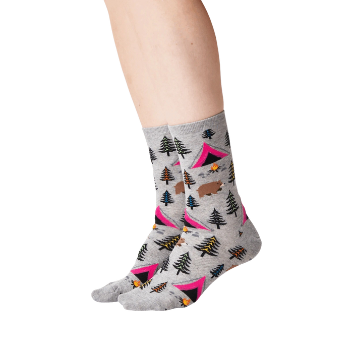 A pair of gray socks with a pattern of pink tents, green and blue pine trees, brown bears, orange campfires, and yellow and blue mountains.