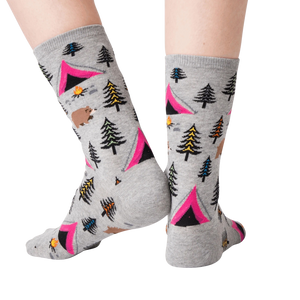 A pair of gray socks with a pattern of pink tents, green and blue pine trees, brown bears, orange campfires, and yellow and blue mountains.