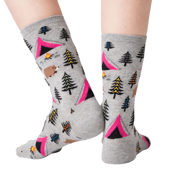 A pair of gray socks with a pattern of pink tents, green and blue pine trees, brown bears, orange campfires, and yellow and blue mountains.