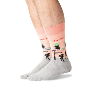 A pair of pink and gray socks with a pattern of Bourbon Street in New Orleans, including musicians and palm trees.