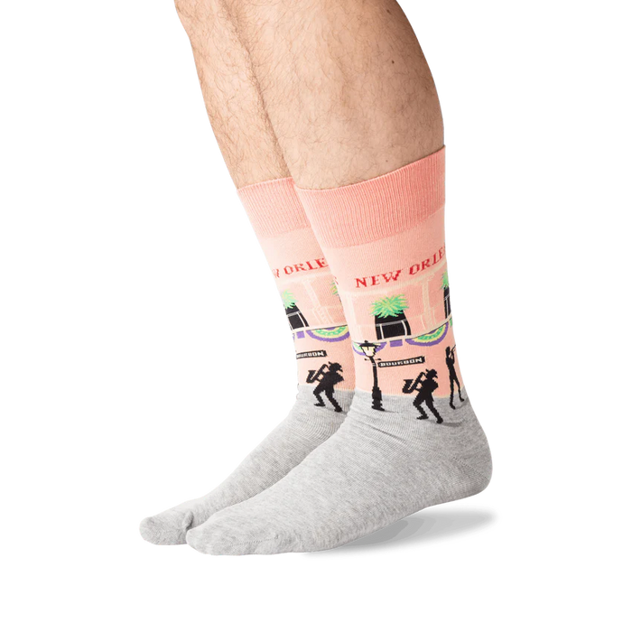A pair of pink and gray socks with a pattern of Bourbon Street in New Orleans, including musicians and palm trees.