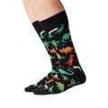 Lifestyle shot showing the dinosaur socks on a person's legs against a green background.