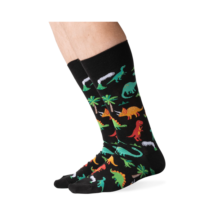 Lifestyle shot showing the dinosaur socks on a person's legs against a green background.