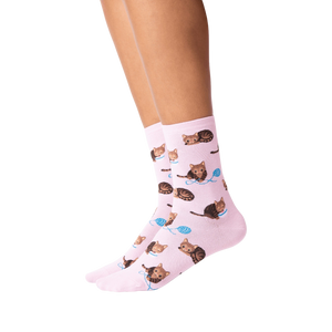 A pair of pink socks with a pattern of brown tabby cats playing with blue yarn balls.