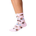 Lifestyle shot: Person's legs wearing pink socks with a repeating pattern of brown cats and yarn.