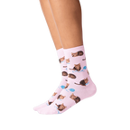 Lifestyle shot: Person's legs wearing pink socks with a repeating pattern of brown cats and yarn.