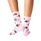 Back view lifestyle shot: Person's legs wearing pink socks with a repeating pattern of brown cats and yarn.