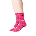 Lifestyle shot showing a person wearing a pair of pink Classic Cats socks. The socks are crew length and feature a pattern of various cats in black, brown, and white.