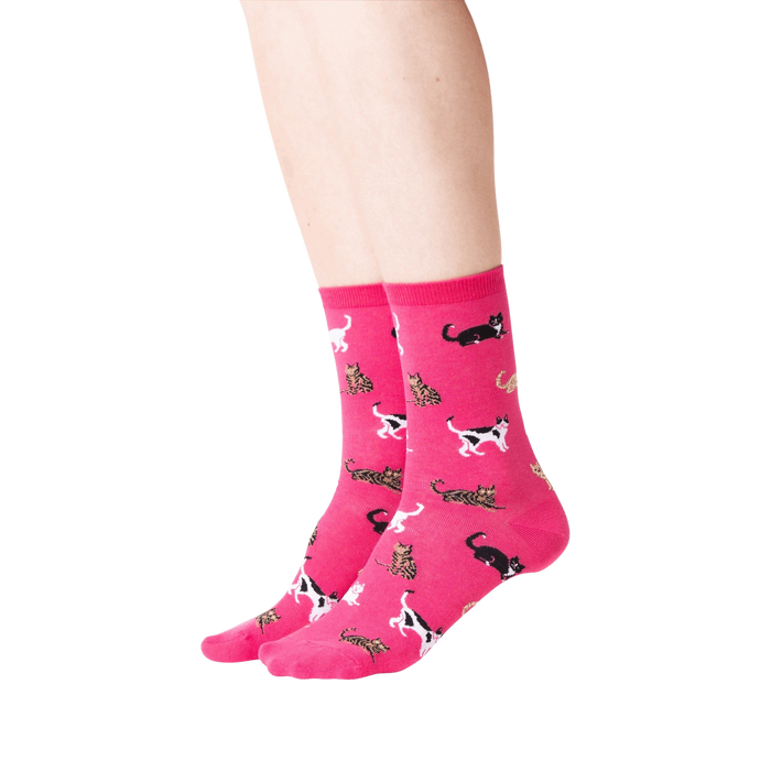 A pair of pink knee-high socks with a pattern of black, white, and orange cats.