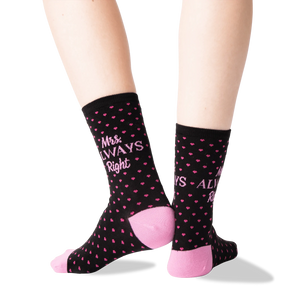 A pair of black socks with pink polka dots and the text 