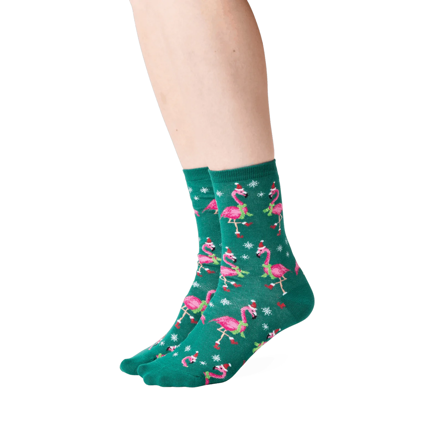 Lifestyle shot: Person wearing dark green crew socks with a pattern of pink flamingos in Santa hats.
