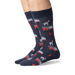 A pair of dark blue socks with a pattern of red fire trucks, black and white dalmatian dogs, and red fire hydrants.