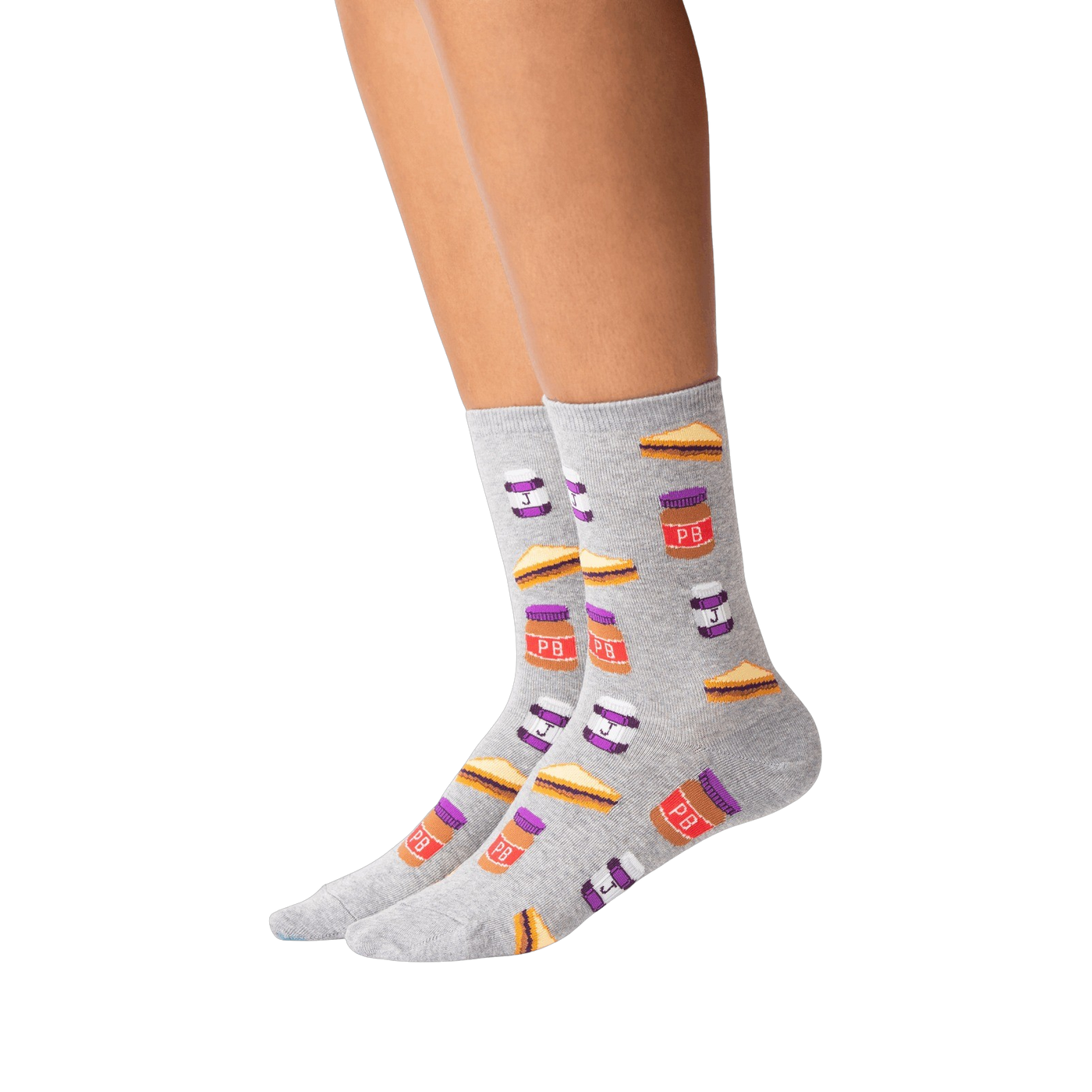 Lifestyle shot of a person wearing a pair of grey Peanut Butter and Jelly crew socks. The socks feature a fun pattern of PB&J sandwiches and jars.
