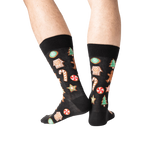 Close-up of a person's legs wearing black Christmas Cookie socks.