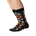 Person's legs wearing black Christmas Cookie socks, shown from the side.