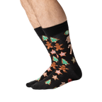Person's legs wearing black Christmas Cookie socks, shown from the side.