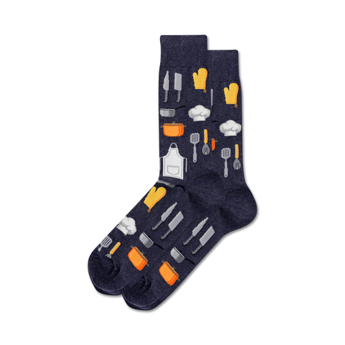 Pair of navy blue crew socks adorned with a fun pattern of kitchen utensils, chef hats, and orange oven mitts.