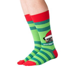 Lifestyle shot showing the socks on a person's feet.  The socks are green and red striped with a pug graphic.