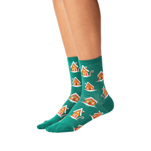 A pair of green socks with a pattern of gingerbread houses and candy canes.