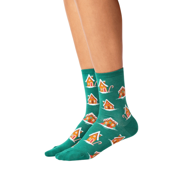 A pair of green socks with a pattern of gingerbread houses and candy canes.