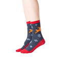 Lifestyle shot showing the socks on a person's feet. The socks are dark gray with red cuffs and toes, featuring a reindeer and snowflake pattern.
