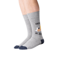 Lifestyle shot of a person wearing the 'Knish Me, I'm Jewish' socks. The socks are gray with a navy blue cuff and feature a knish graphic.
